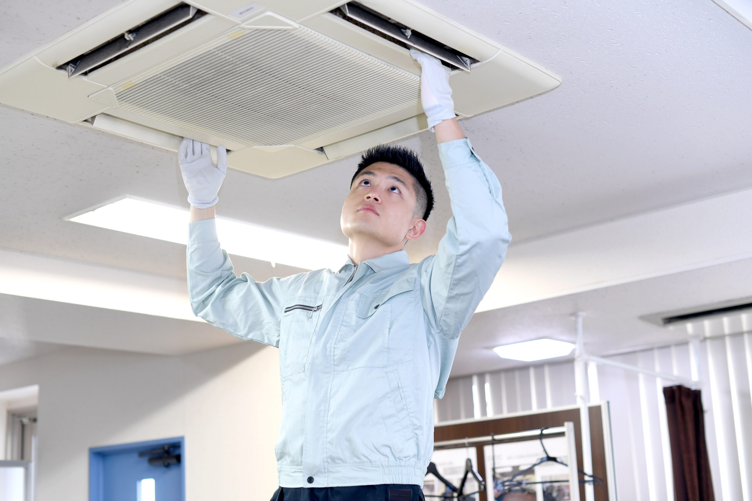 天井埋め込みエアコンをクリーニングする作業員